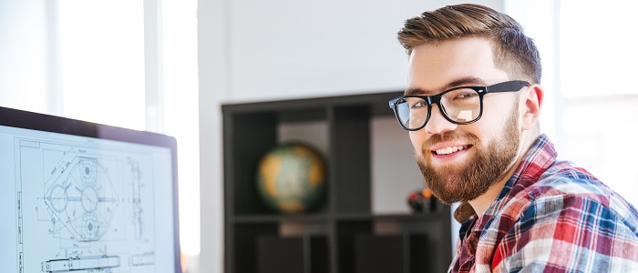 Ein Mitarbeiter von dem Support Team sitzt vor einem Rechner und lächelt. 